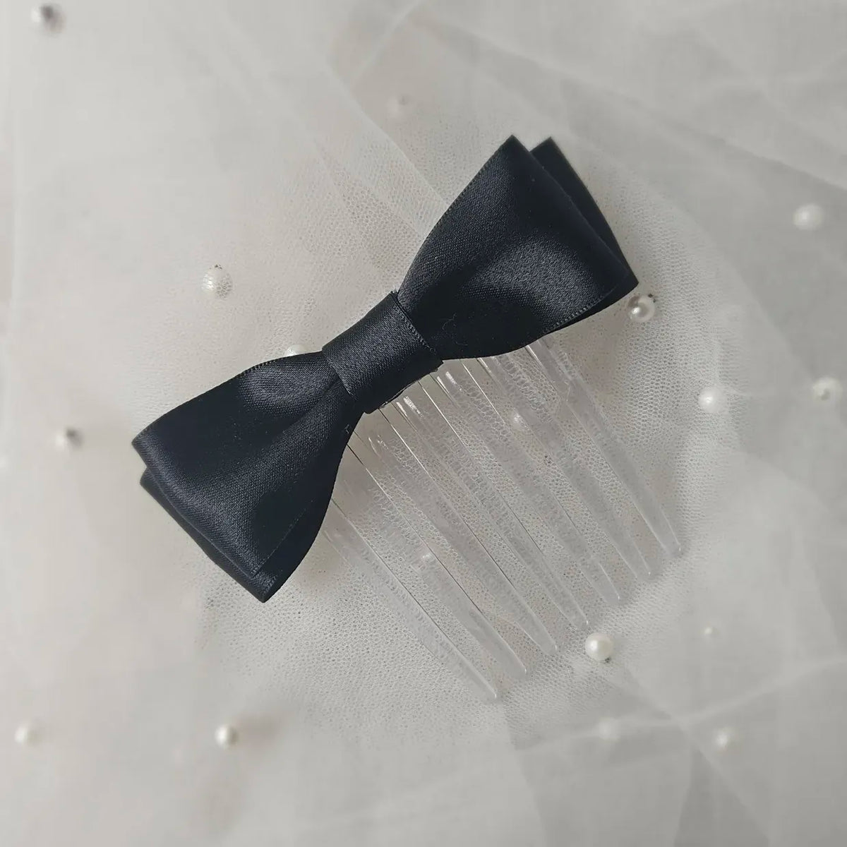 Black satin ballet exam bow on a clear hair comb, designed for classical ballet examinations