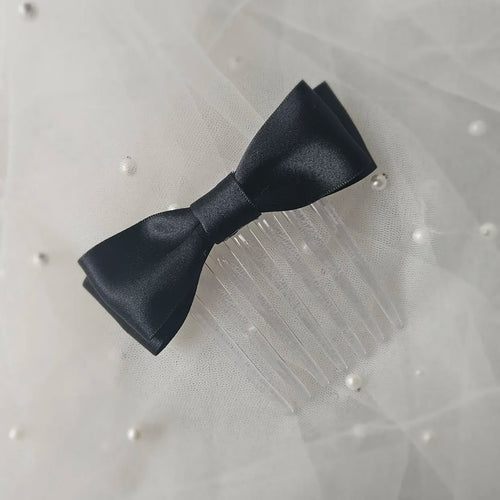 Black satin ballet exam bow on a clear hair comb, designed for classical ballet examinations