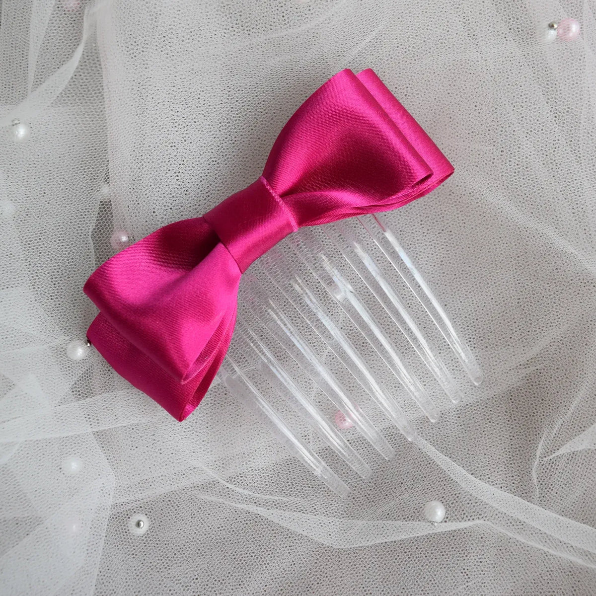 Fuchsia satin ballet exam bow on a clear hair comb, designed for classical ballet examinations