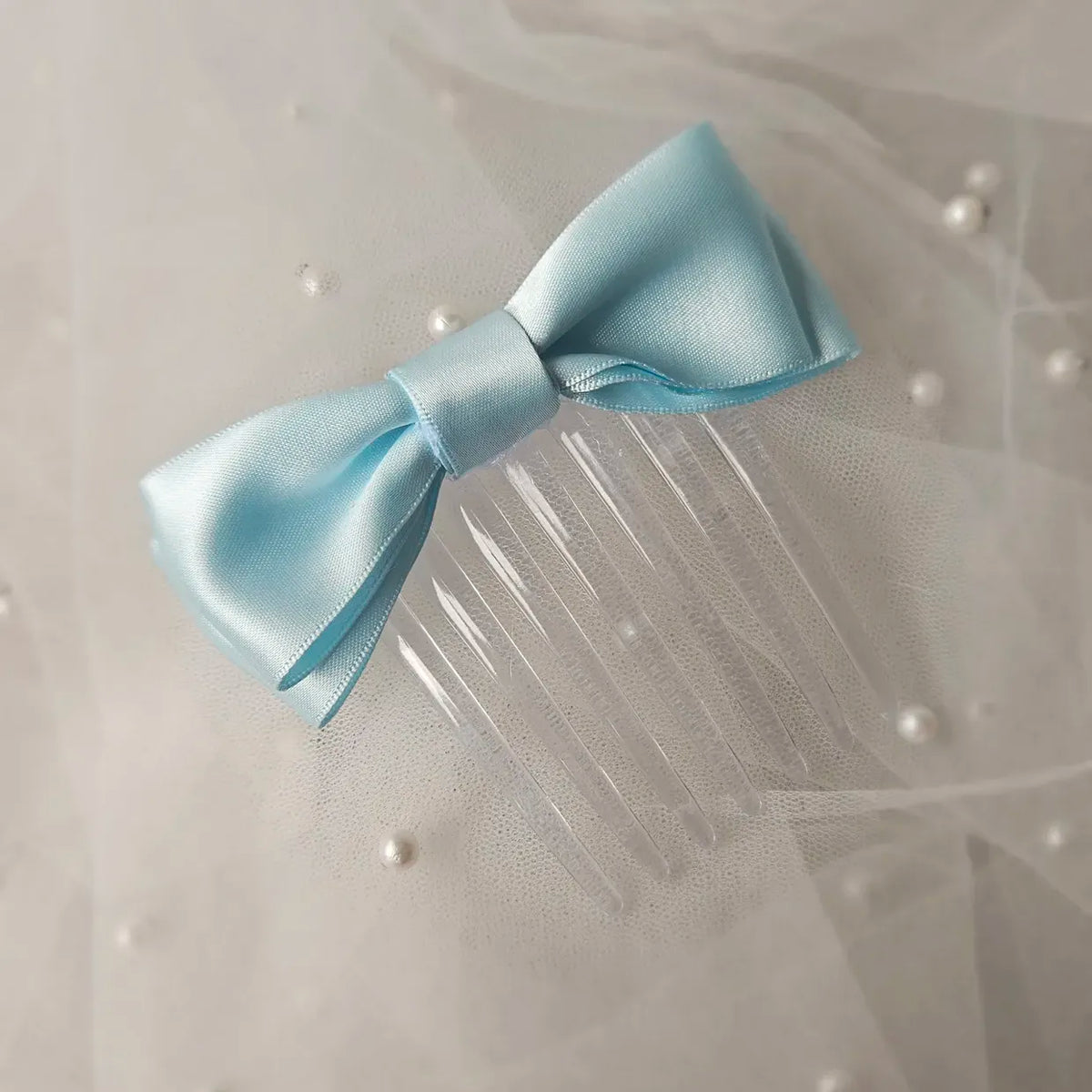 Light blue satin ballet exam bow on a clear hair comb, designed for classical ballet examinations