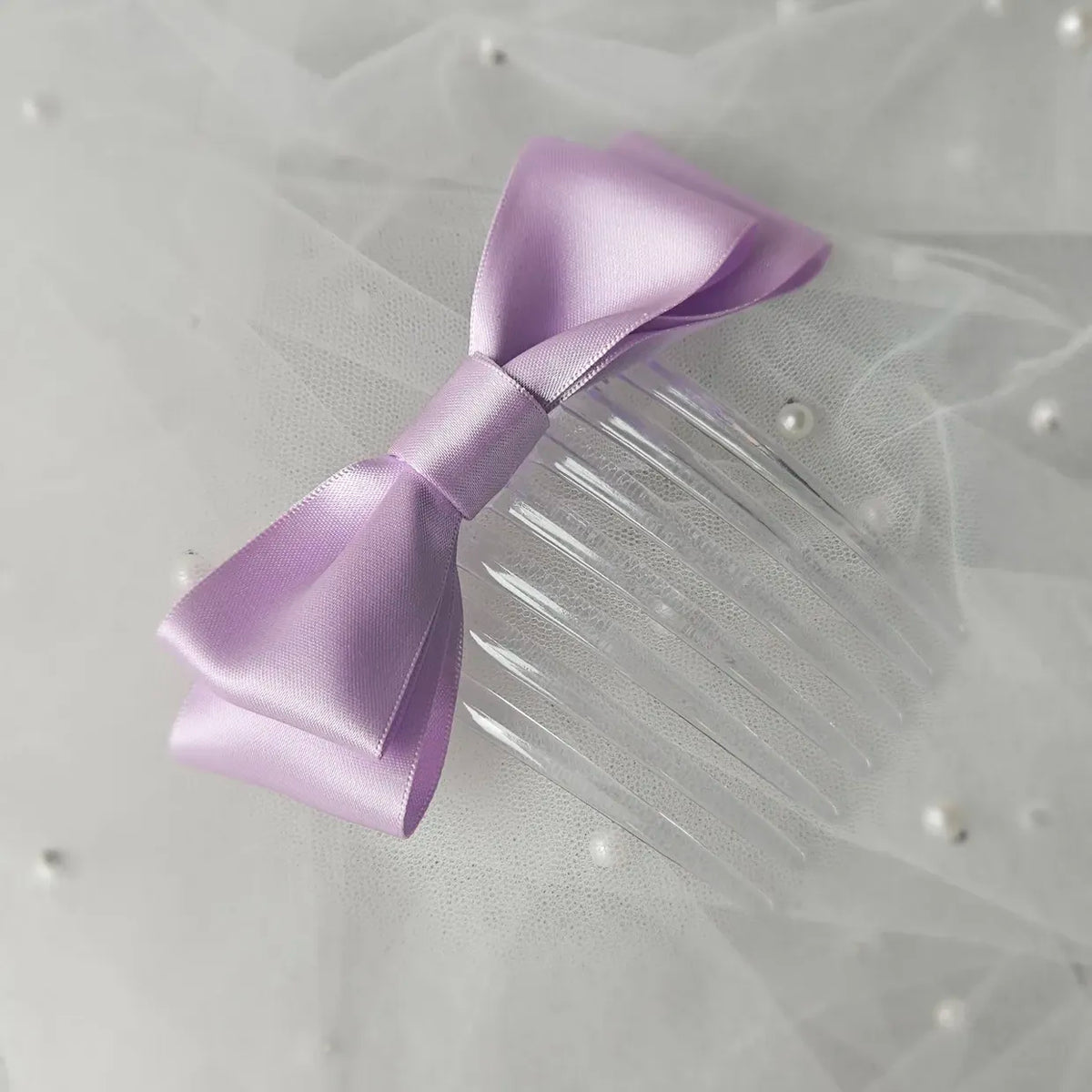 Lilac satin ballet exam bow on a clear hair comb, designed for classical ballet examinations