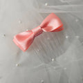 Peach satin ballet exam bow on a clear hair comb, designed for classical ballet examinations
