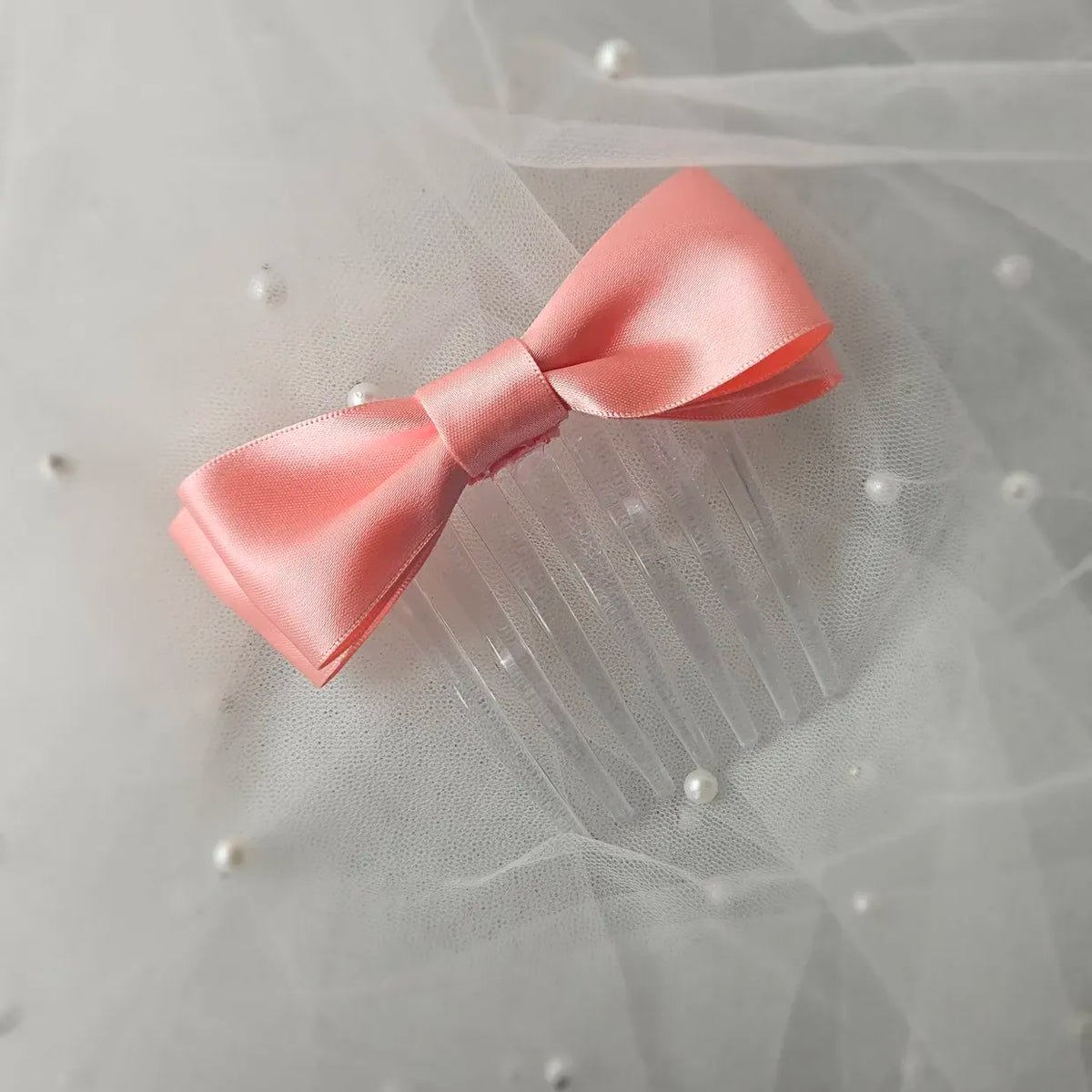 Peach satin ballet exam bow on a clear hair comb, designed for classical ballet examinations