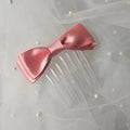 Rose pink satin ballet exam bow on a clear hair comb, designed for classical ballet examinations