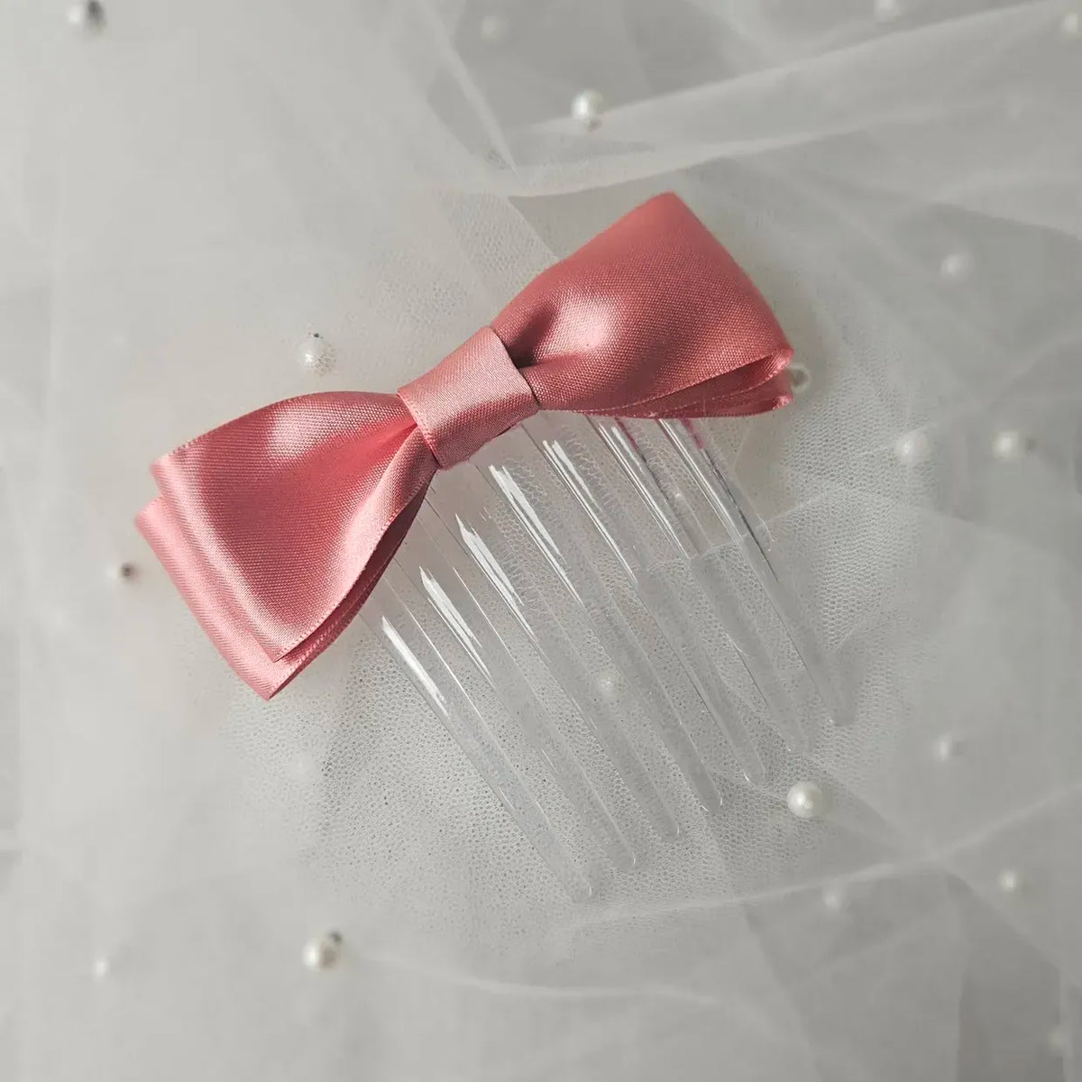 Rose pink satin ballet exam bow on a clear hair comb, designed for classical ballet examinations
