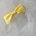 Yellow satin ballet exam bow on a clear hair comb, designed for classical ballet examinations